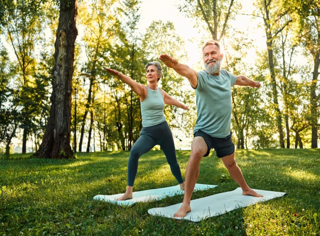 Senior couple practicing yoga in a park to enhance eye health and prevent vision diseases like macular degeneration.