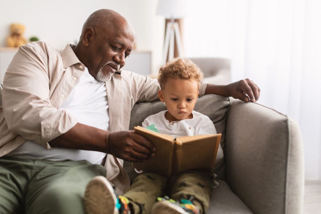 Grandfather reading a book with his grandchild, symbolizing improved vision with MacuMira Vision Therapy.