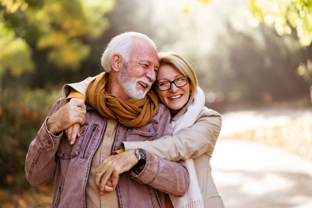 Happy senior couple enjoying a walk outdoors, representing improved quality of life with MacuMira Vision Therapy.