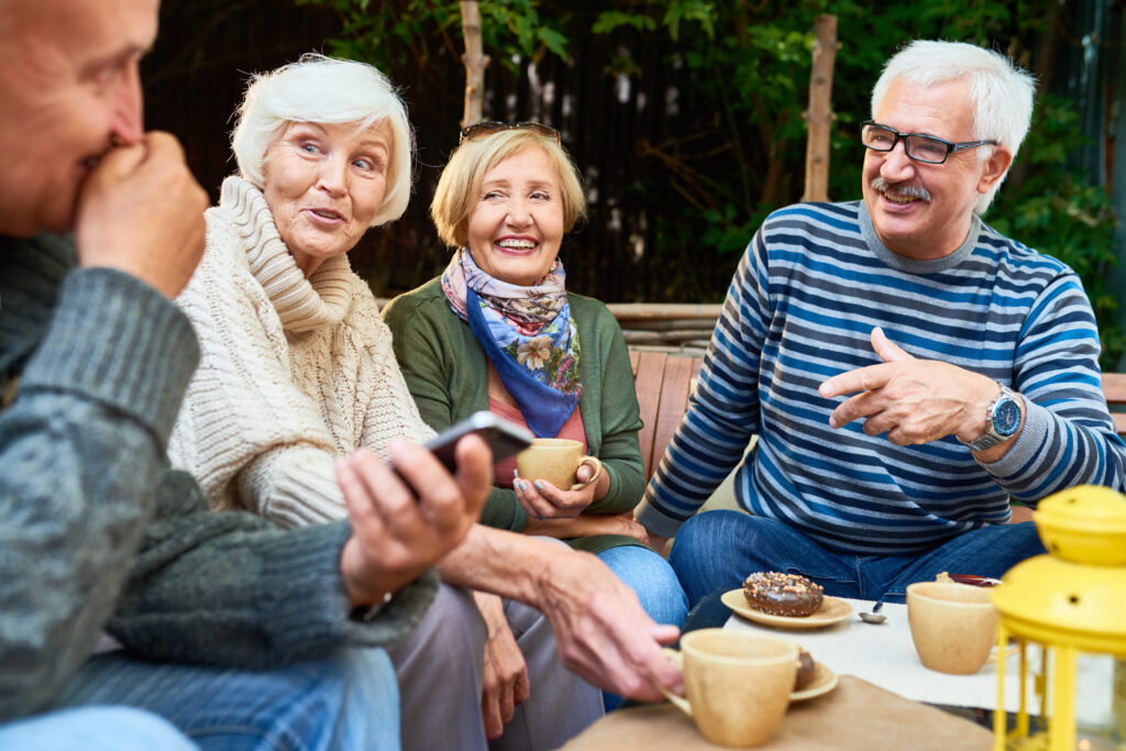 Group of seniors enjoying coffee and conversation outdoors, sharing laughs and good company.